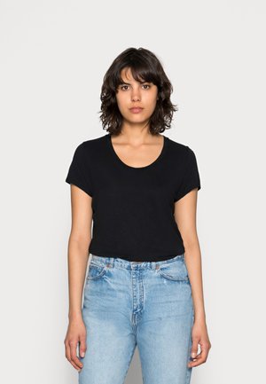 Black short-sleeve t-shirt with a scoop neckline, paired with high-waisted light blue jeans. The fabric appears smooth and lightweight.