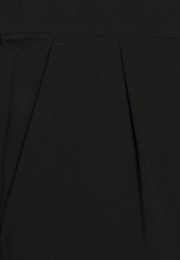 Schwarzer Stoff mit Falten-Detail und glatter Textur. Das Material scheint strapazierfähig zu sein und eignet sich für strukturierte Kleidung.