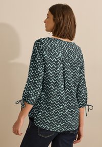 Dunkelbluse mit einem Zickzackmuster in Hellblau, dreiviertelärmel mit Bindebändern, aus weichem, strukturiertem Stoff, lässige Passform.