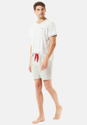 Camiseta de rayas grises y blancas de manga corta, combinada con shorts grises con un cordón rojo. Fondo blanco.