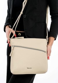 Sac en cuir beige à bandoulière avec une finition texturée, doté d'une fermeture éclair supérieure et d'une poche zippée supplémentaire à l'avant.