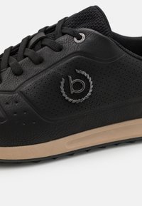 Black sneaker with leather upper, textured mesh tongue, perforations, and rubber outsole. Features logo accent and black laces.