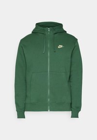 Grön zip-up hoodie gjord av strukturerad tyg, med en kenguruficka och en guld Nike-logotyp på vänster bröstområde.