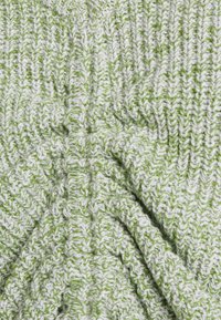 Tecido malhado verde e branco com um padrão zigzag texturizado e costura visível, criando uma aparência suave e convidativa.