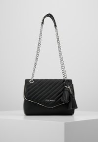 Borsa a tracolla nera trapuntata con catena argentata, dettagli borchiati e chiusura con patta. Presenta un dettaglio a frange su un lato.