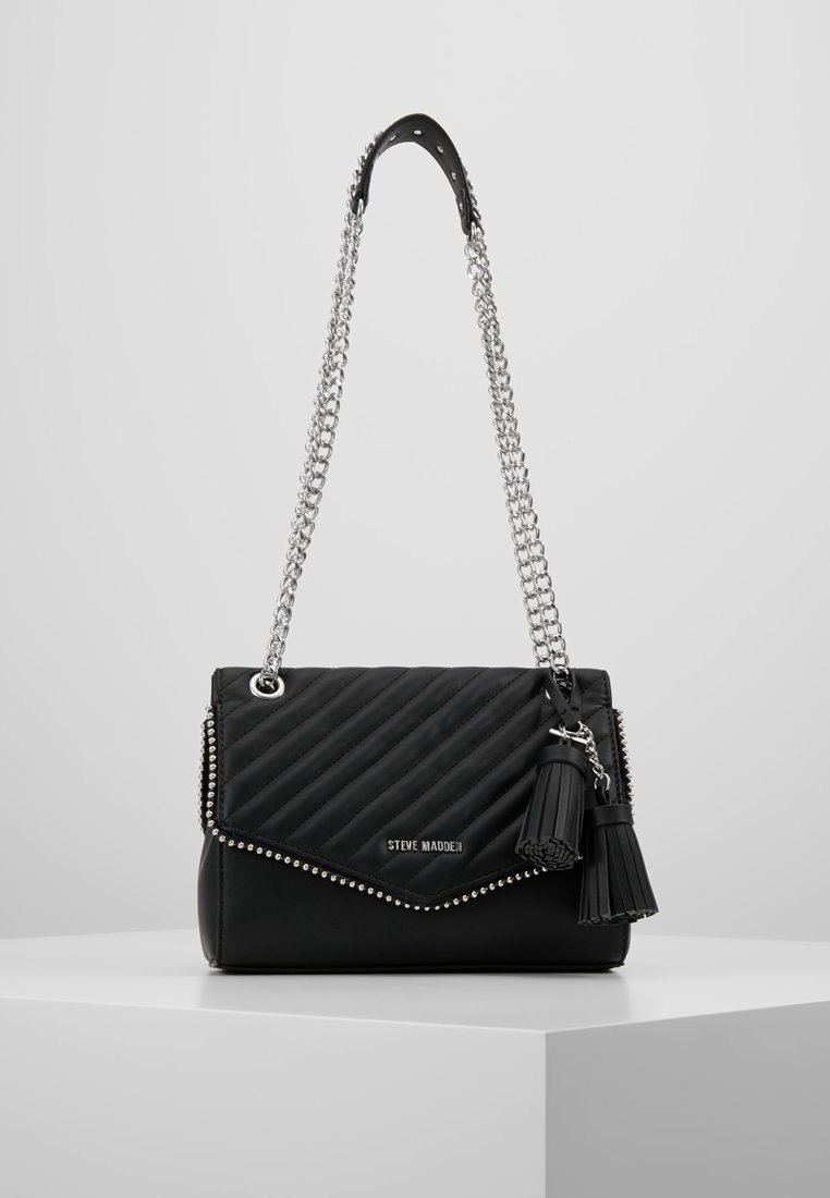 Borsa a tracolla nera trapuntata con catena argentata, dettagli borchiati e chiusura con patta. Presenta un dettaglio a frange su un lato.