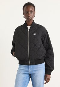 Must mustriga bomber-jakk, millel on soonikkoes ja mansetid, esi tõmblukk ning väike logopatch vasakul küljel.