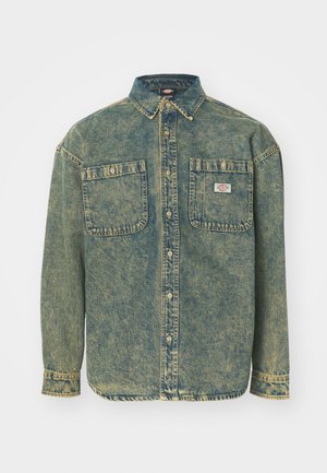 Camicia in denim con un lavaggio azzurro chiaro, maniche lunghe, colletto a punta, due tasche sul petto e cuciture a contrasto. Presenta un'etichetta del marchio sulla tasca.