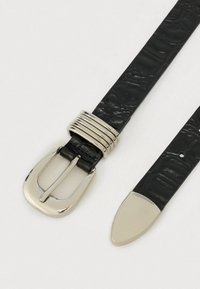 Must nahast vöö krokodillinahkse mustriga, hõbedase tooniga pandla ja metallist detailidega. Kitsenev ots sileda viimistlusega.