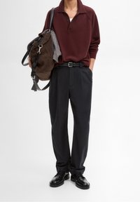 Bordeaux polo shirt met een kraag, zwarte broek en zwarte schoenen. De tas is van bruin suede met een grijze bovenkant. Inclusief een zwarte riem en bandjes.