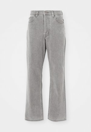 Jean en denim gris clair avec une taille haute, des jambes évasées et des détails de couture visibles. Comprend des poches avant et une fermeture éclair.