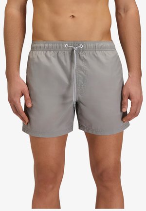 Uomo che indossa pantaloncini da bagno grigio chiaro con fascia elastica in vita e cordino bianco, mostrato da metà busto a metà coscia.
