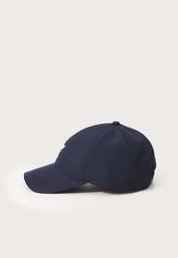 Navy blue cap with rigid brim, made of smooth fabric. Features stitched seams and a round top, designed for an adjustable fit.