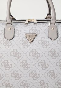 Sac à main gris clair avec un motif en losanges, patte avec un logo imprimé en relief, accents en cuir et doubles poignées supérieures. Détails en métal doré.