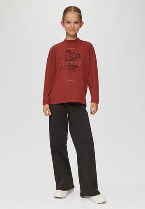 Rotes Langarmoberteil mit dem Aufdruck "dreamy" und floralem Design, kombiniert mit schwarzen weit geschnittenen Hosen und weißen Turnschuhen. Glatte Stofftextur.