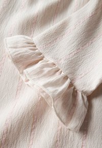 Tessuto rosa chiaro con sottili righe e delicati fili dorati. Il dettaglio arricciato all'orlo migliora la texture e il design.
