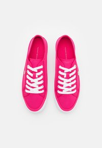 Vaaleanpunaiset kangastennarit, joissa valkoiset nauhat, kumipohjat ja logo painettuna sisäpohjiin. Sileä pinta ja pyöristetty muotoilu.