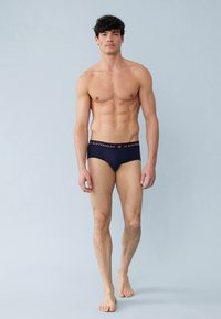 Middenblauwe mannenonderbroeken met een zwarte elastische tailleband waarin de merknaam "LE SLIP FRANÇAIS" in het wit staat. Katoenen materiaal, getailleerd ontwerp.