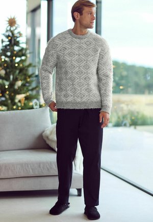 Szary, puszysty sweter w romby, połączony z czarnymi spodniami i czarnymi butami. Naturalne światło podkreśla miękką teksturę.