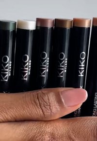 Åtte KIKO Milano sminkestifter ordnet vertikalt med svarte rør merket i sølv. Lokket er i forskjellige farger, inkludert grønn, hvit og brune.