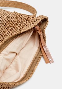 Wiklinowa torba na ramię w odcieniu brązowym z zamkiem błyskawicznym. Bawełniana podszewka w jaśniejszym odcieniu i skórzana metka z nazwą marki.