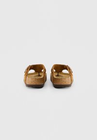 Καφέ σουέτ σανδάλια με δύο ρυθμιζόμενες ίνες, φελλό σταθερή σόλα, ανάγλυφο καουτσούκ σόλα και διάτρητο σχέδιο στα πλάγια.