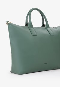 Borsa a mano in pelle verde texturizzata con due manici robusti, forma strutturata e un logo sottile sul davanti. Presenta una chiusura con zip.
