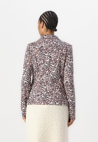 Blazer s leopardím vzorem v růžových, bílých a černých tónech, se střihem na míru, dlouhými rukávy a hladkou texturou látky.