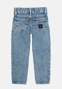 Jeans de denim azul claro con corte recto, cinco bolsillos y un parche de logo en el bolsillo trasero derecho. Textura desgastada en toda la prenda.