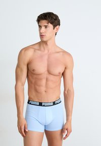 Boxeri scurți de culoare albastră deschisă, fabricați dintr-un material moale, având un brâu elastic negru pe care este inscripționat cu litere mari "PUMA".