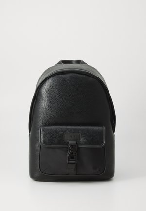 Sac à dos en cuir noir avec une finition texturée, forme incurvée, poche avant avec fermeture à clip, et poignée supérieure rembourrée. Fermeture éclair sur le compartiment principal.