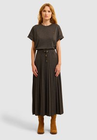Grijze, relaxed-fit t-shirt met korte mouwen, gecombineerd met een geplooide, lange donkere rok met een verstelbare koordtaille en gouden accenten.
