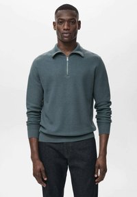 Grayish-green pullover sweater with a zippered collar, ribbed cuffs, and hem, made from textured knit fabric. Worn over dark jeans.