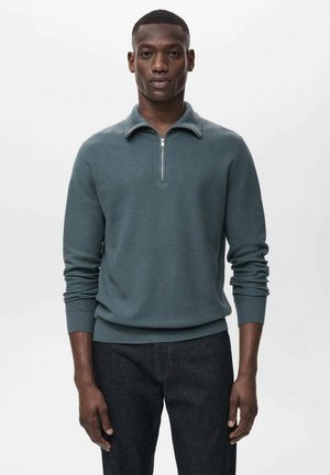 Grayish-green pullover sweater with a zippered collar, ribbed cuffs, and hem, made from textured knit fabric. Worn over dark jeans.