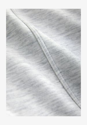 Gaiši pelēks audums ar mīkstu, teksturētu virsmu. Raksturots ar smalku jauktu toņu rakstu un redzamām šuvēm gar malām.