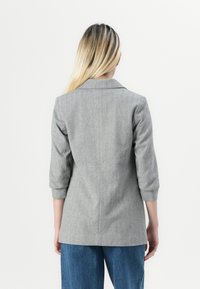 Grijze houndstooth blazer met driekwartmouwen, notch-kraag en een getailleerde pasvorm, gecombineerd met lichtblauwe denim broek.