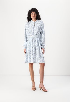 Light blue floral dress with long sleeves, a gathered waist, and a buttoned collar. Worn with strappy tan high-heeled sandals.