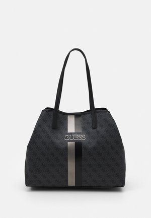 Black Guess tote bag with patterned logo print, two straps, and vertical beige and black stripes on front center.