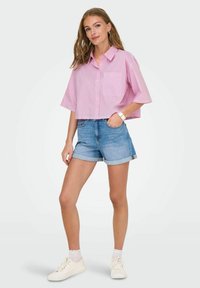 Lyserød og hvidstribet kortærmet skjorte med knaplukning, cropped design, sammen med lyseblå denim shorts. Hvide sneakers fuldender outfittet.