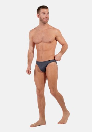 Graue Schwimmbriefe mit einem niedrigen Schnitt. Hergestellt aus dehnbarem Stoff, mit minimaler Naht und einem kleinen Logoetikett am Bund.