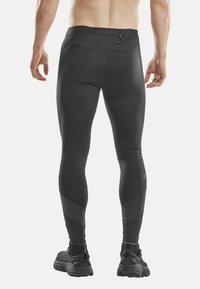 Zwarte sportleggingen met een aansluitend ontwerp, voorzien van een achterzak en gestructureerde accenten op de onderbenen. Geschikt voor actieve kleding.