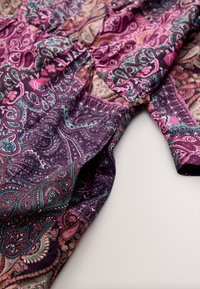 Bluză multicoloră cu un model paisley în nuanțe de mov, roz și teal. Material ușor, cu detalii adunate în talie.