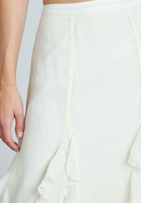 Gonna midi plissettata bianca con dettagli a ruches lungo i bordi. Tessuto leggero con una texture liscia e vita elastica.