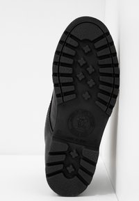 Black boot sole with deep treads, featuring a circular logo reading "Natural Life & Style," size 37, made in Spain.