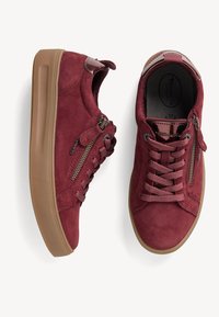 Sneaker in suede rosso con punta rotonda, caratterizzati da una suola testurizzata, chiusura con lacci e zip laterale. Include colletto imbottito e dettagli tonali.