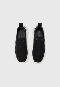 Pantofi slip-on negri din plasă, cu partea superioară texturată, având o talpă albă din cauciuc și accente cu ținte de-a lungul părții superioare. Logo-ul este vizibil pe talpă.