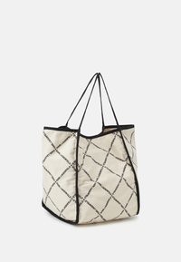 Torba z tkaniny w kolorze off-white z czarnym wykończeniem. Posiada geometryczny wzór z tekstem "KARL LAGERFELD" w powtarzającym się układzie diamentów.