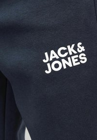 Marineblauwe joggingsbroek van zachte stof met een opvallend wit "JACK & JONES" logo aan de zijkant. Eenvoudig, relaxed ontwerp.