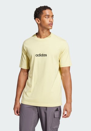 Camiseta de algodón amarilla con mangas cortas, que presenta un logotipo negro de "adidas" centrado en el pecho. Cuello redondo simple y corte relajado.