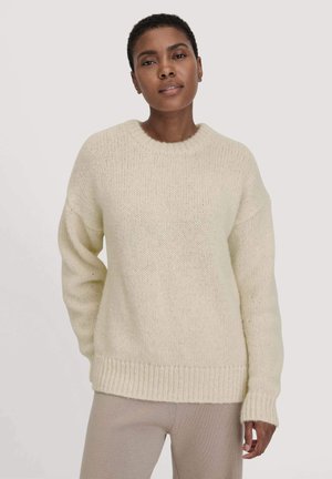 Strickpullover in Creme mit Rundhalsausschnitt, überschnittenen Schultern und gerippten Bündchen. Weiche Textur mit lässiger Passform und einer leicht übergroßen Silhouette.